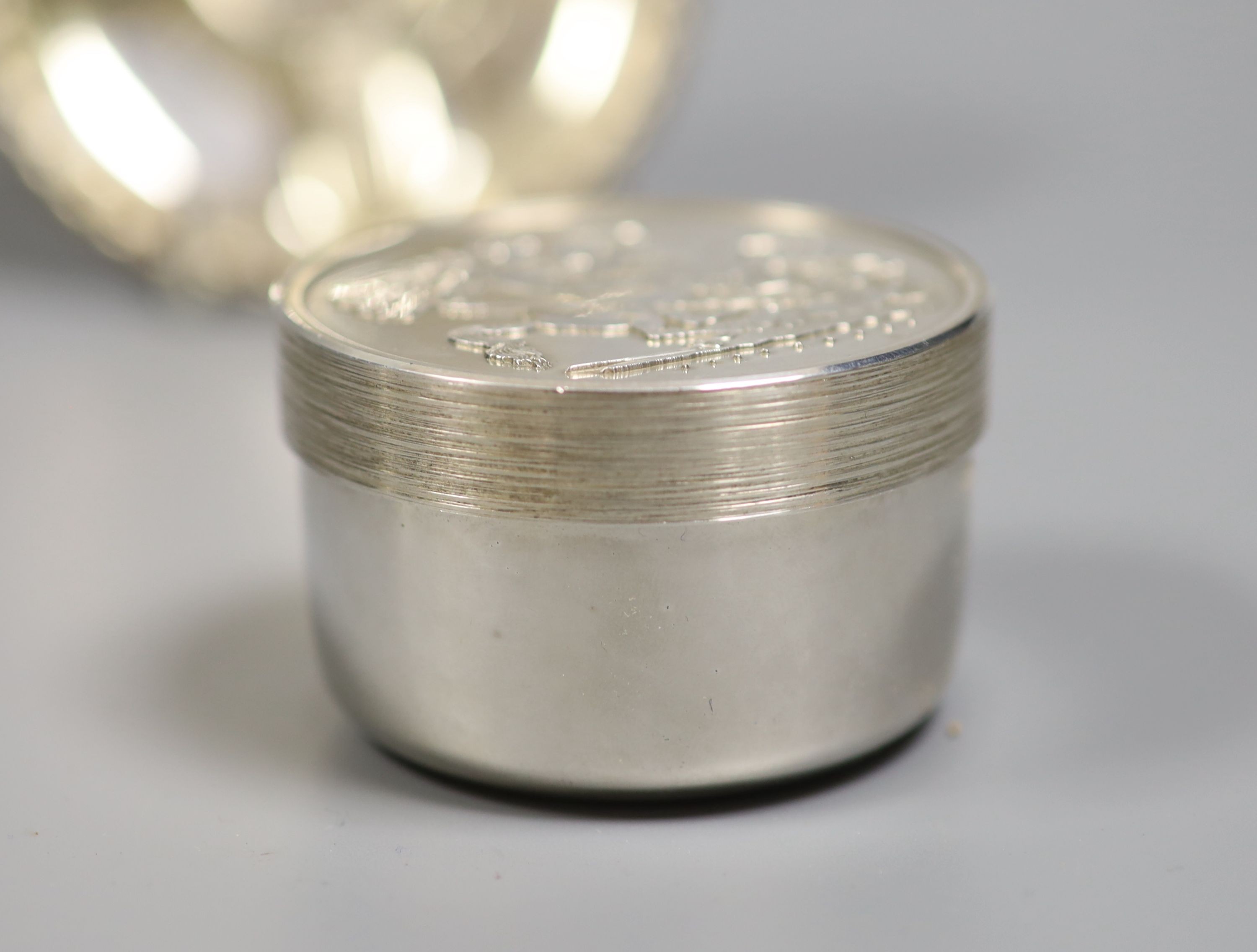 A modern silver pot and cover, decorated with St. George & The Dragon, diameter 61mm and a cased silver plaque, both by Christopher Nigel Lawrence.